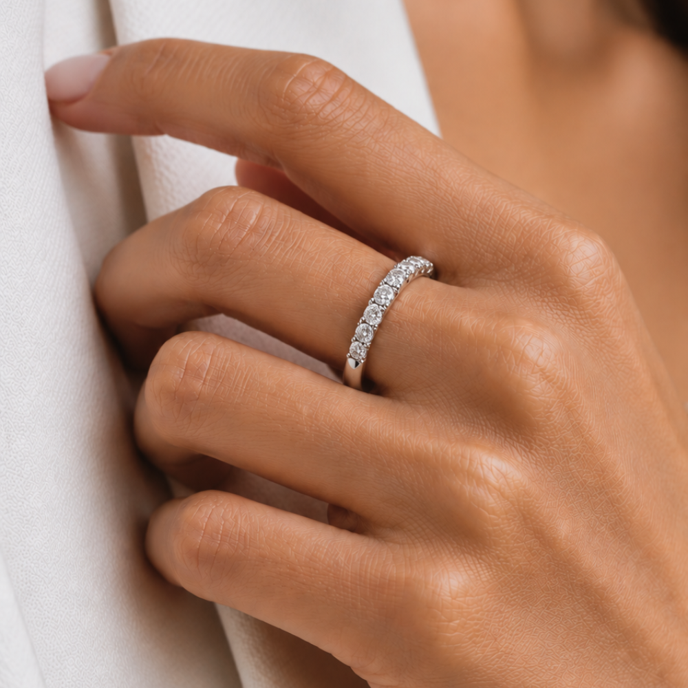 A close-up of a hand wearing a 10K gold diamond half-eternity ring, resting against a white textured fabric.
