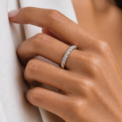 A close-up of a hand wearing a 10K gold diamond half-eternity ring, resting against a white textured fabric.