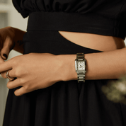Person wearing a silver citizen watch on a blurred background