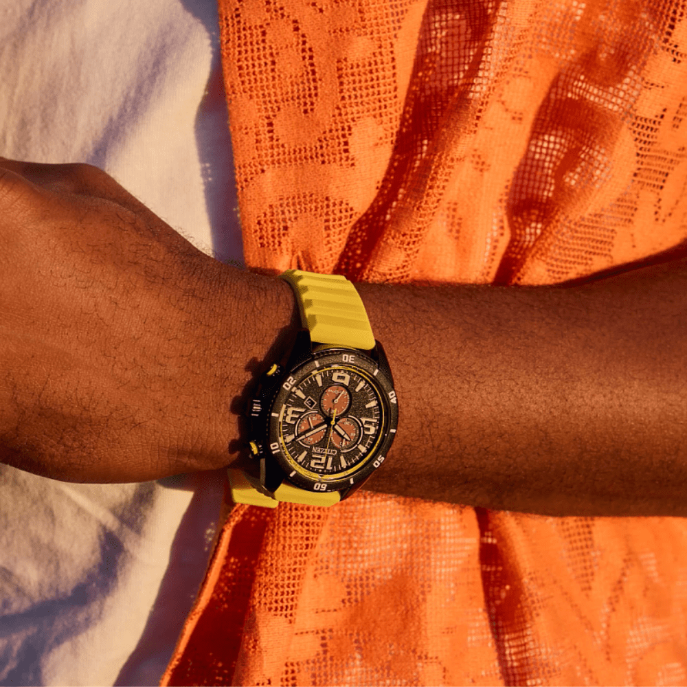 The wrist of a man wearing a citizen yellow strap eco-drive watch