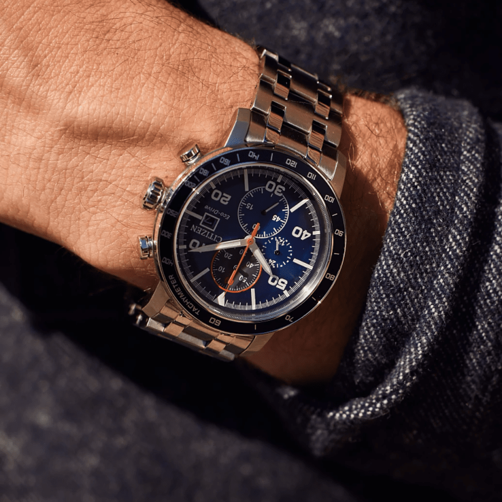 Close-up of a wrist wearing a silver citizen watch with a blue face.