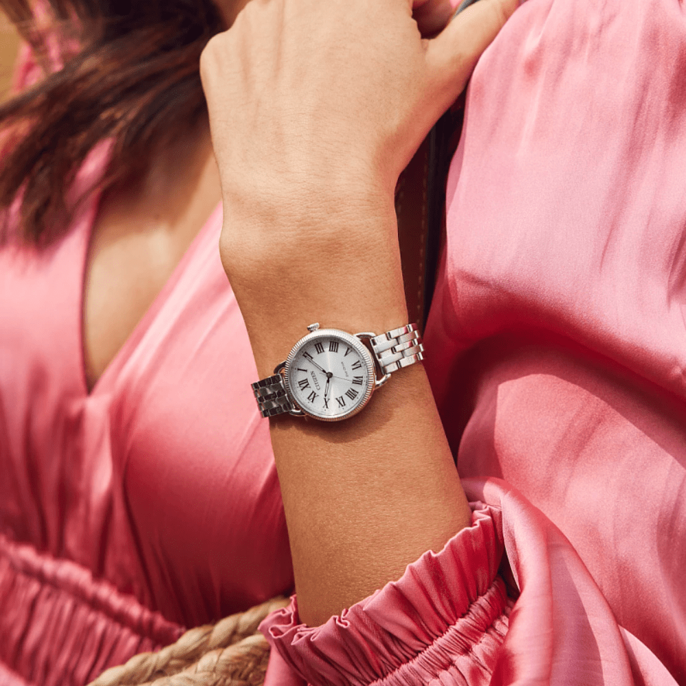 Silver  citizen eco-drive watch on a wrist with a pink dress