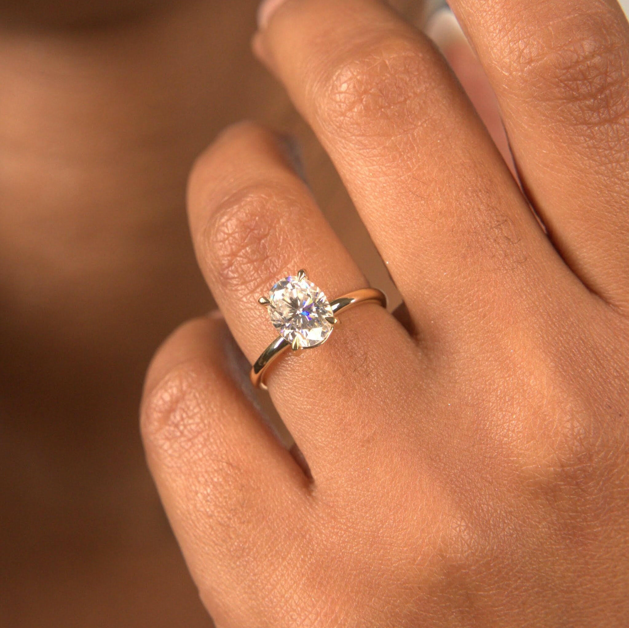 Woman wearing oval solitaire lab diamond ring engagement style