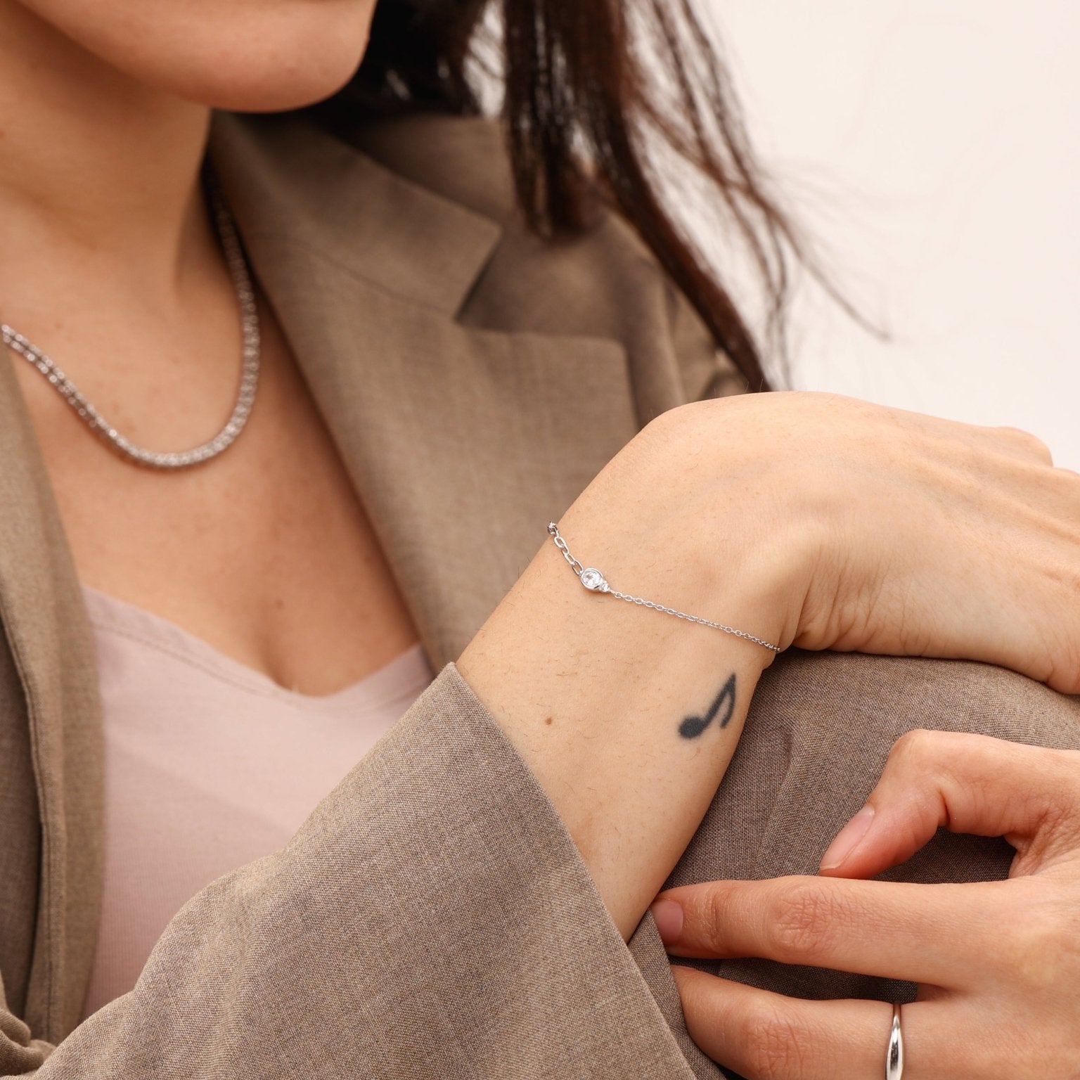 Woman wearing a bracelet and ring with a neutral background