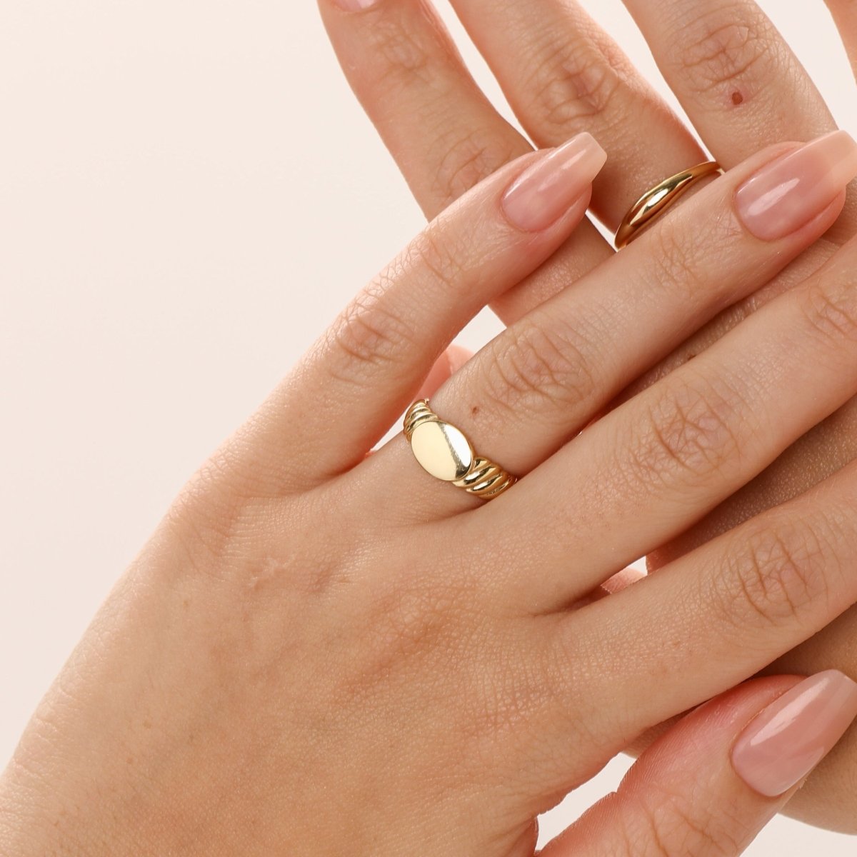 Person wearing torsade signet ring in gold classic modern style